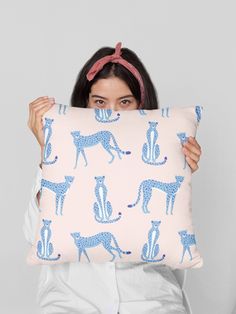 a woman is holding up a pillow with blue cats on it and she has her eyes closed