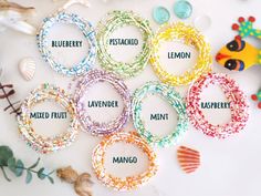 several bracelets with names on them sitting next to sea shells and seashells