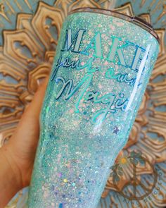 a hand holding a blue and white glittered tumbler with the words mardi gras on it