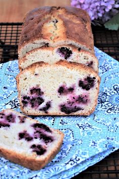 a loaf of blueberry bread sitting on top of a blue and white cloth next to a piece of cake