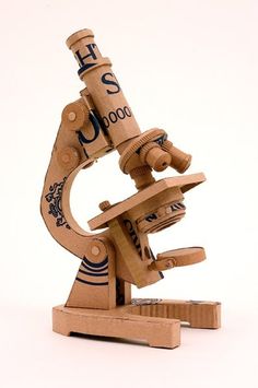 a wooden model of a microscope on a white background