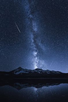 the night sky is filled with stars, and there are mountains in the foreground