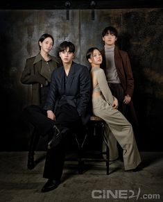 three people are sitting on a chair in front of a dark background and one person is wearing a suit