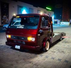 a red truck parked on the side of a road at night with its lights on