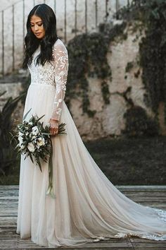 a woman in a wedding dress standing on a wooden floor holding a bouquet and looking at the camera