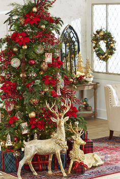 a christmas tree decorated with red and gold ornaments, deer figurines and poinsettis