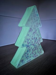 a glass christmas tree sitting on top of a wooden table