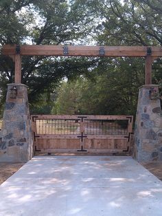 a gated in area with stone pillars and gates on both sides, surrounded by trees