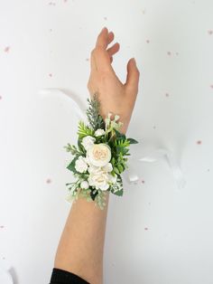 a woman's hand with a flower wrist corsage on top of it