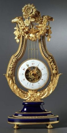 an ornate clock with blue and gold decorations on it's sides, sitting on a table