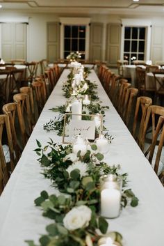 a long table with candles and greenery on it is set up for an event