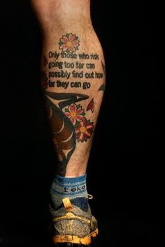 a man's legs with tattoos and words on them, in front of a black background