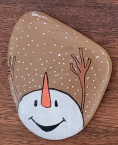 a painted rock with a smiling snowman on it