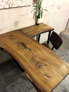 a wooden table with two chairs next to it and a potted plant in the corner