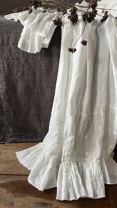 a white dress with pine cones hanging from it's shoulders on a wooden floor