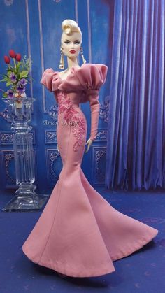 a barbie doll wearing a pink dress with flowers on the head and shoulders, standing in front of a blue background