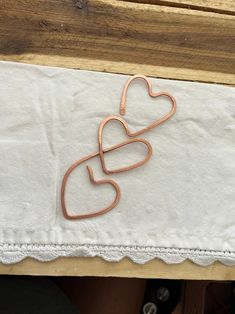 a pair of heart shaped paper clips sitting on top of a white cloth covered table