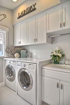 a washer and dryer in a white laundry room next to a window with the word laundry on it