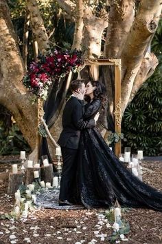 a man and woman kissing in front of a wooden frame with candles on the ground