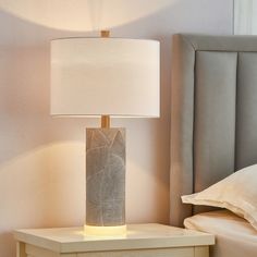 a lamp on a night stand next to a bed