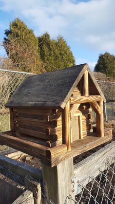 a wooden bird house on top of a fence