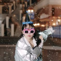 a woman wearing sunglasses and a party hat in the snow with her hand on her hip