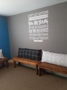 two wooden benches in front of a gray wall with words on the wall behind them