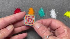 two hands are holding beaded objects on a table