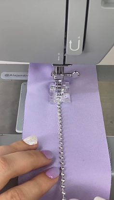 someone is using a sewing machine to sew something on the purple paper that they are holding