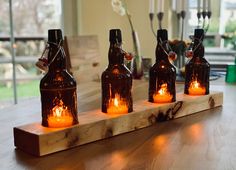 four brown bottles with lit candles in them sitting on a table