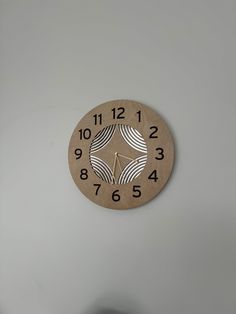 a wooden clock on the wall with numbers and symbols in black lettering, against a white background