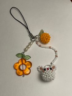 two beads are attached to a keychain with an orange flower and a white sheep