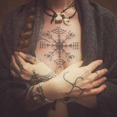 a woman with tattoos on her chest holding hands in the shape of a snowflake