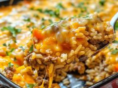 a spoonful of mexican rice and ground beef is being lifted from a casserole dish