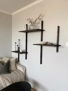 a living room with two shelves on the wall and a couch in front of it