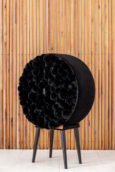 a black chair with flowers on it in front of a bamboo wall