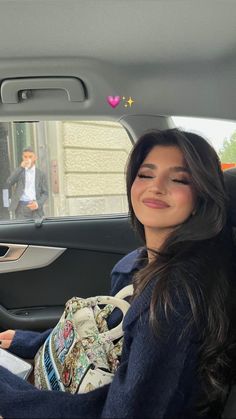 a woman sitting in the back seat of a car with her eyes closed and smiling