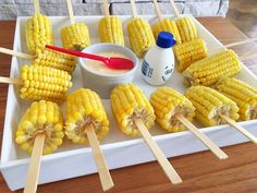 corn on the cob with ketchup and toothpicks sitting on a tray