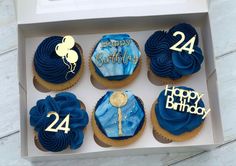 cupcakes with blue frosting and gold numbers in a box