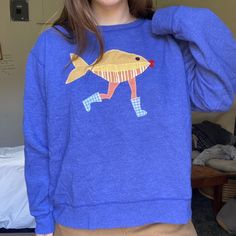 a woman wearing a blue sweater with an image of a fish on it's back