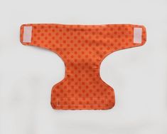 an orange bib with white polka dots on the front and back, sitting against a white background