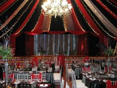 the inside of a tent decorated with red, white and black tables set for an event