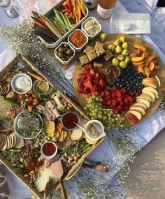 two trays filled with different types of food on top of a white table cloth