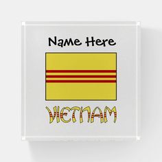 the name here is written in yellow and red on a white square tile wall plaque