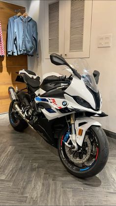 a white and black motorcycle parked inside of a building next to a coat hanger