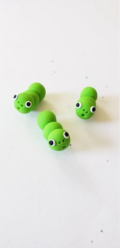 several green beads with black dots and eyes on them sitting on a white table top