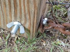 an old wooden post with nails and chains attached to it, in the middle of some grass