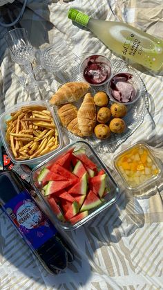 there are many different types of food in the trays on the table, including watermelon and croissants