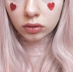 a close up of a person with pink hair and hearts painted on her face,