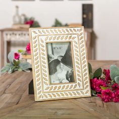 a wooden table topped with flowers and a photo frame